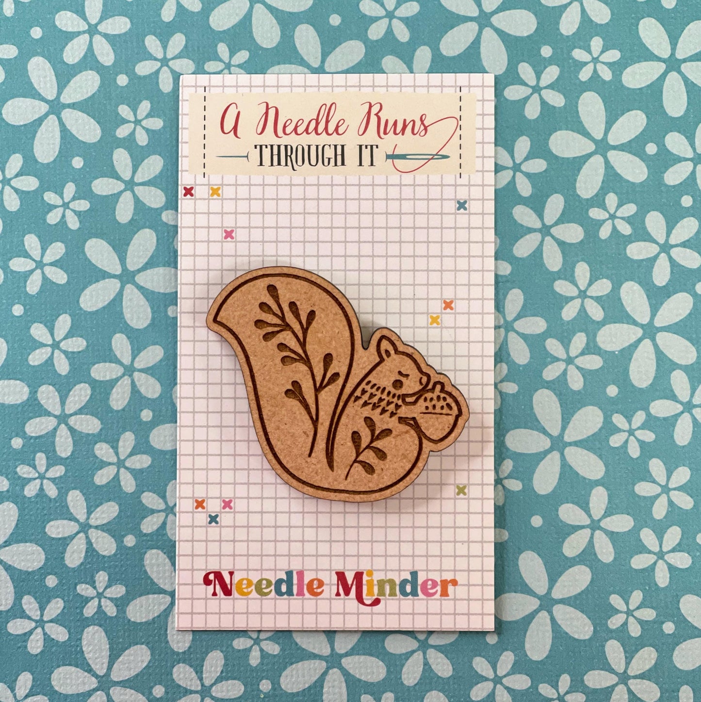 a wooden squirrel needle minder holding an acorn