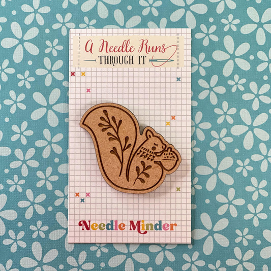 a wooden squirrel needle minder holding an acorn